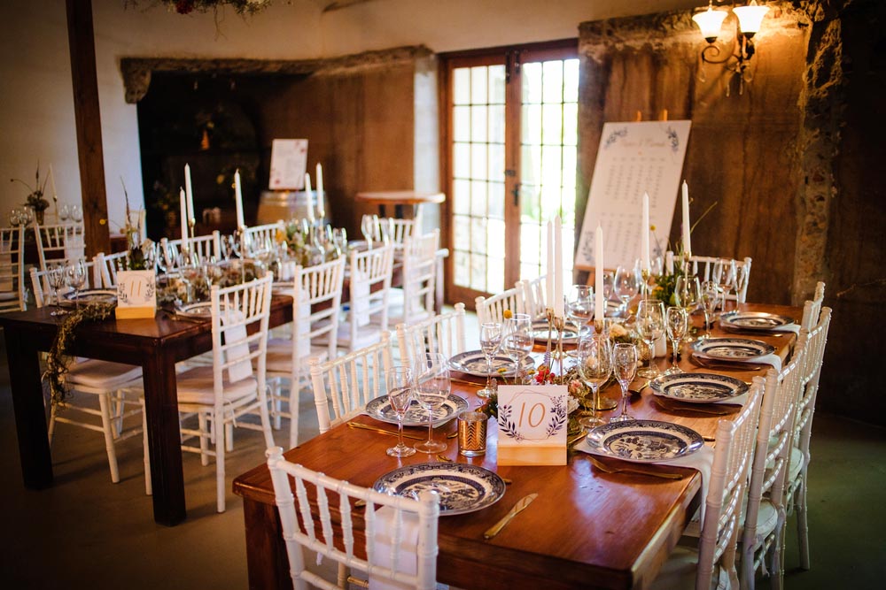 This captivating image showcases the elegant decor and stunning floral arrangements of a real wedding. The photograph features a beautifully decorated table in a charming wedding venue, adorned with delicate flowers, candles, and other decorative elements. The exquisite details of the decor, including the carefully arranged centerpieces and intricate table settings, create a romantic and enchanting atmosphere. The soft, natural lighting further enhances the ambiance, providing a warm and inviting feel to the photograph. This image is perfect for a range of uses, including wedding invitations, event planning, and romantic advertisements.