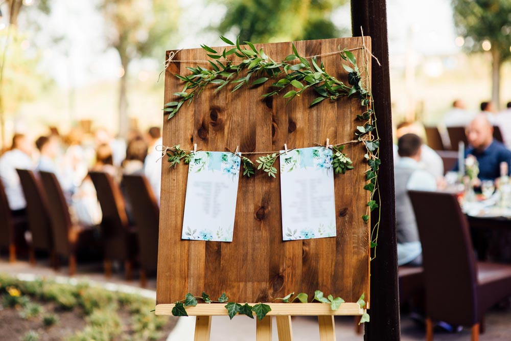 Original vintage wooden board with decoration and ribbons and a guest list, heart and bucket in the background. with a place for an inscription
