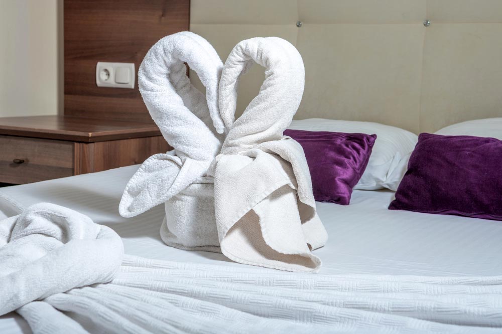 Two towel swans. Two swans made of towels forming heart shape on bed in honeymoon suite room hotel. romantic interior
